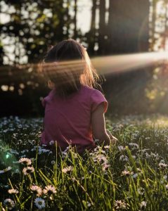 girl sitting on daisy flowerbed in forest