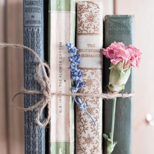 four assorted-title books tied up with a cord and flowers