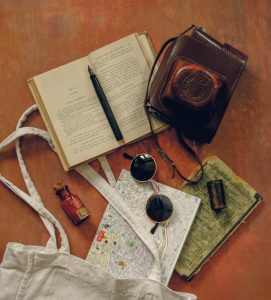 a photo machine bag, a book, a pen, and a pair of glasses on a table