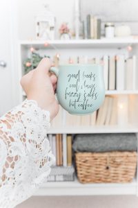 green ceramic cup with sayings and book shelves behind